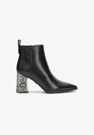 Fekete bőr bokacsizma hegyes orral és díszített tömbsarkal, amely több téglalap- és négyzetalaku kristályszerű részletet tartalmaz.