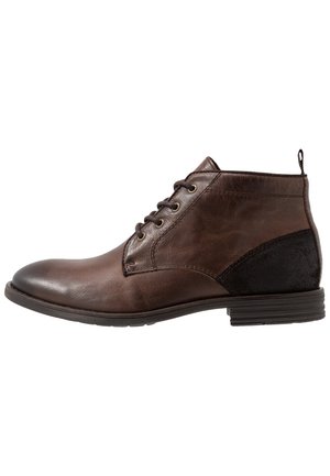 Bottine en cuir marron avec panneau talon en daim noir, lacets à l'avant et semelle basse empilée.