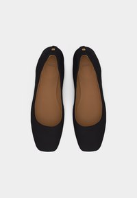 Ζευγάρι μαύρα μπαλαρίνα με τετράγωνα μύτη και ταμπά εσωτερικά πέλματα, σε θέα από πάνω πάνω σε λευκό φόντο.