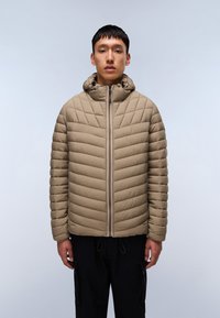 Giacca a vento beige imbottita con motivo a rombi, collo alto e chiusura con zip. Presenta un cappuccio e orlo elasticizzato. Indossata con pantaloni scuri.