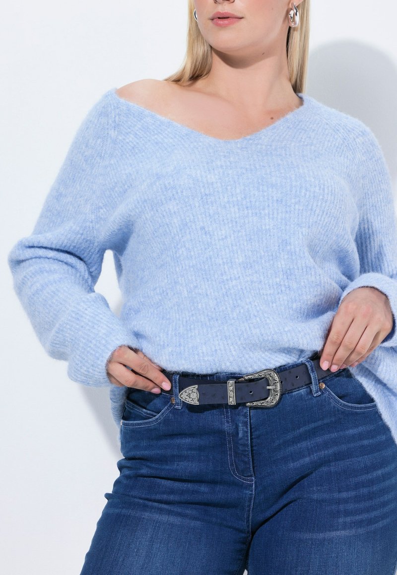 Suéter de punto azul claro con escote en V y textura acanalada, combinado con jeans azul oscuro y un cinturón negro con hebilla plateada grabada.