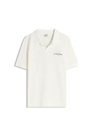 Fehér póló pamut anyagból, klasszikus gallérral, rövid ujjakkal és egy diszkrét barna logóval a bal mellen.