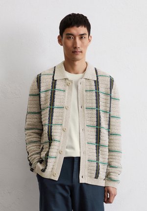 Gestrickter beiger Cardigan mit strukturierter Oberfläche, der ein Karomuster mit blauen, grünen und gelben Akzenten aufweist; Knopfverschluss vorne und Kragen.