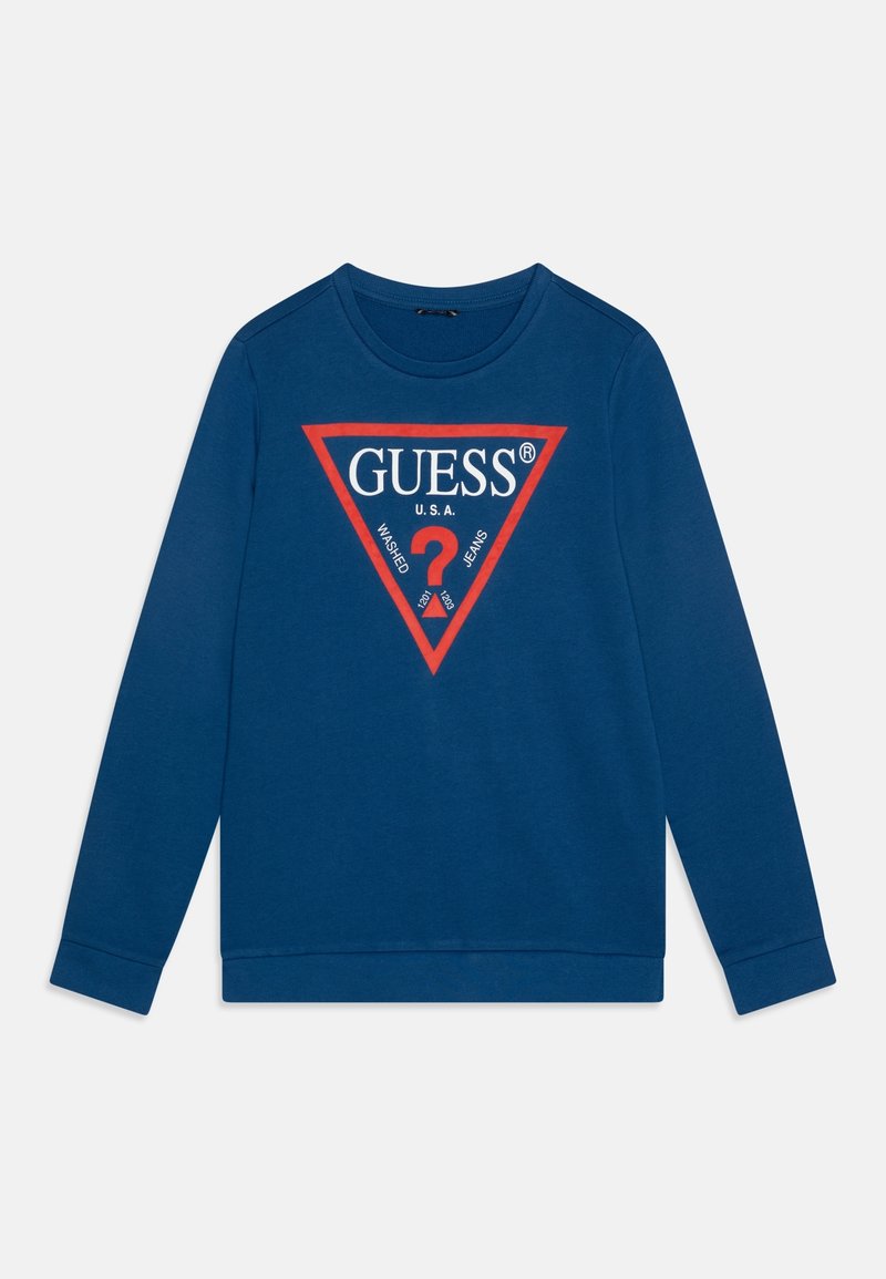 T-shirt bleu à manches longues avec col rond, présentant un triangle rouge avec "GUESS U.S.A." et un logo point d'interrogation blanc et rouge sur la poitrine.