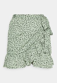 Jupe portefeuille verte avec un motif abstrait noir, blanc et vert. Dispose d'un ourlet à volants et d'une attache à nouer sur le côté. Texture de tissu douce.