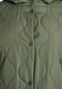 Zaļa kapučveida jaka ar viļņotas raksta šuvēm, sprādzītēm un gludu auduma tekstūru. Kapuce nodrošina papildu siltumu.