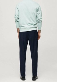 Hellblaues Sweatshirt mit gerippten Bündchen und Saum, kombiniert mit dunkelblauen Hosen. Aus weichem Material gefertigt, hat es eine lockere Passform und ein minimales Design.