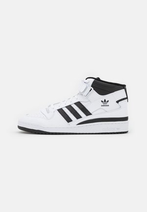 White and black Adidas high-top sneaker with three black stripes, lace-up front, ankle strap, and Adidas logo on the side and sole.
