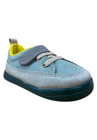 Zapato de lona azul claro con acentos de gamuza gris, cordones elásticos y una correa de Velcro. Interior amarillo y suela de goma oscura. Forma redondeada.