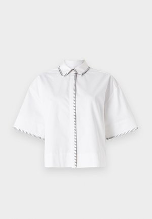 Chemise blanche à manches courtes en coton, avec un col classique et des accents de couture noire le long du col et des poignets.