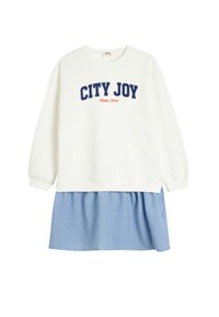 Hvid sweatshirt med teksten "CITY JOY" i marineblå, der har en blå og hvidstribet nederdel fastgjort i taljen. Blødt bomuldsmateriale, afslappet pasform.