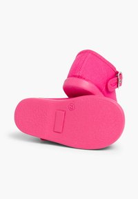 Rosa Knöchel-Schuh aus flexiblem Material mit einer strukturierten Sohle. Verfügt über einen einfachen Riemen mit einer silbernen Schnalle an der Seite.