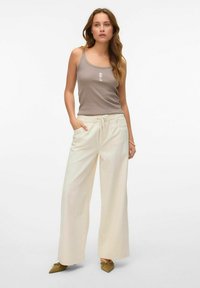 Gai bežīgas bikses ar platām kājām, ar aukliņu jostasvietā un sānu kabatām, apvienotas ar pieguļošu pelēku topu ar jūras zirdziņa dizainu.