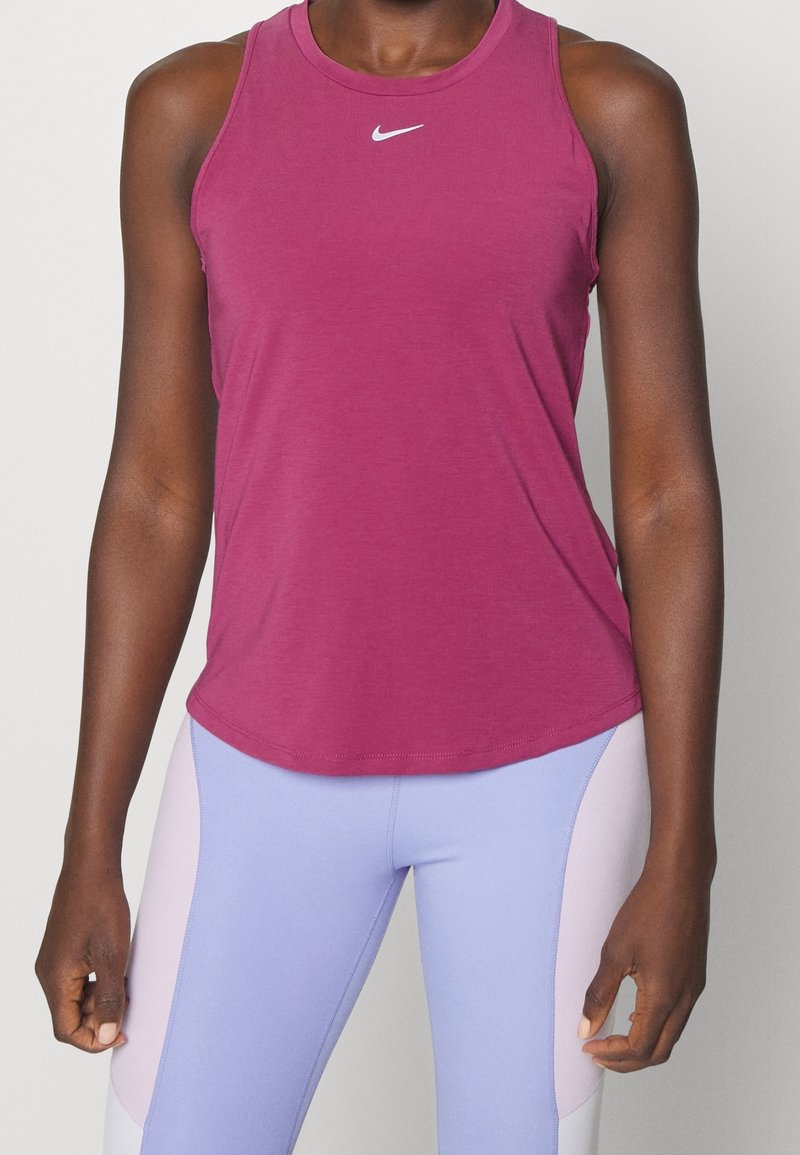 Fioletowy top na ramiączkach z okrągłym dekoltem i bez rękawów. Na piersi małe białe logo Nike. Gładki materiał o luźnym kroju.