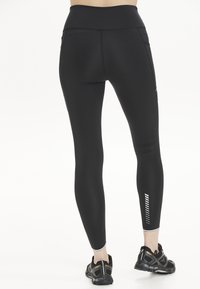 Svarta träningsleggings med hög midja, med sidofickor och reflekterande detaljer på underbenet.