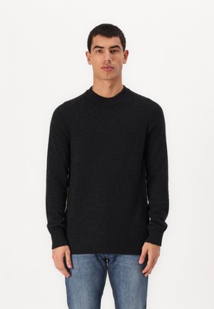 Svart strikkegenser med lange ermer, rund hals og ribbestrikkede mansjetter og kant. Brukt med denimjeans mot en ensfarget bakgrunn.