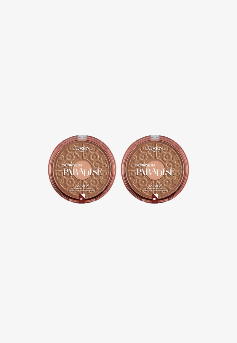 Deux compacts de bronzer circulaires étiquetés "Lever de soleil au paradis", avec des couvercles texturés présentant des tourbillons, dans des tons beige chaud et des fermetures transparentes.