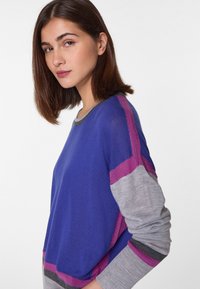 Blauer Pullover mit grauen, lila und kastanienbraunen Akzenten. Hat einen Rundhalsausschnitt und lange Ärmel. Glatte Textur mit lässiger Passform.