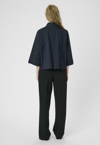 Marine gestreepte blouse met een kraag, wijde mouwen en een rechte snit, gecombineerd met zwarte, strakke broekspijpen. Vloeibare stoftextuur.