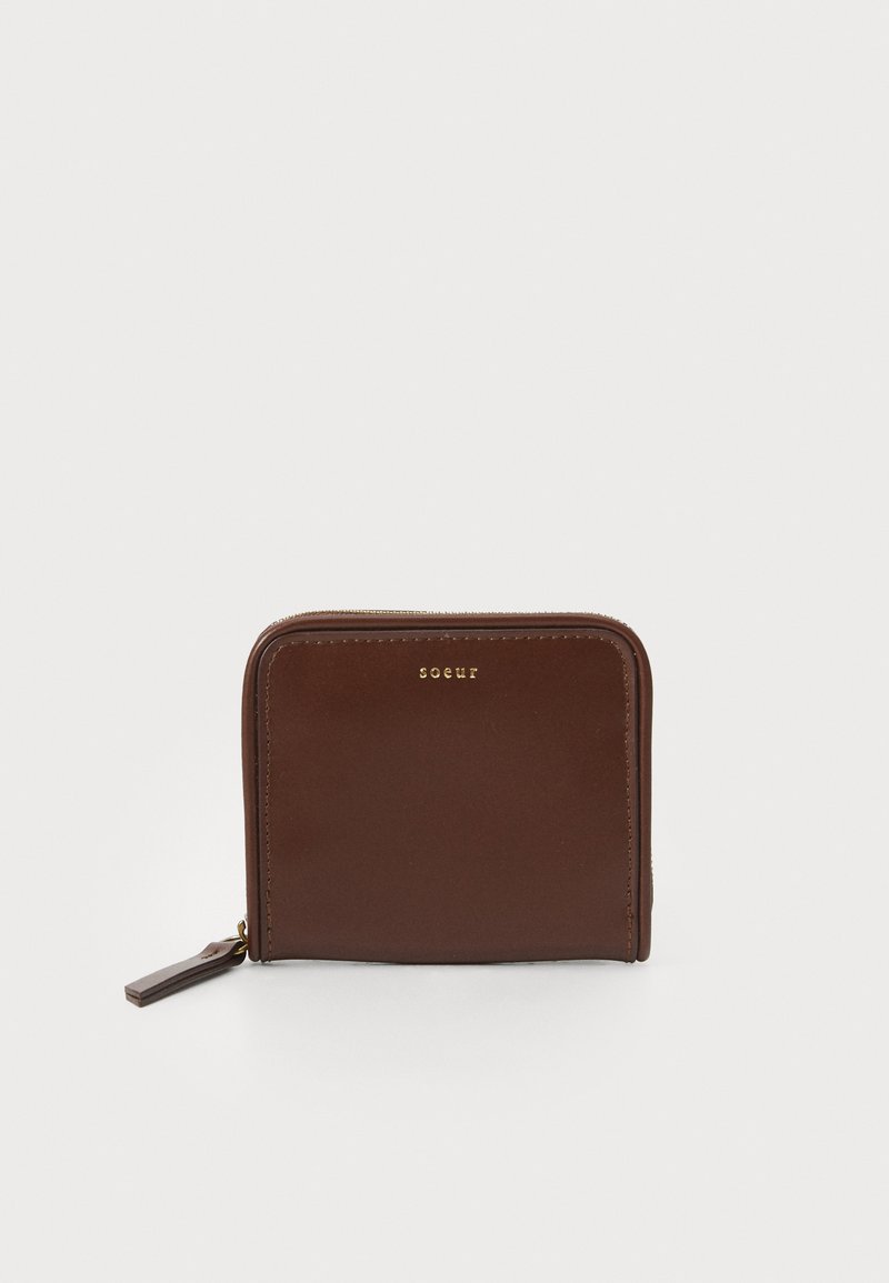 Brūna ādas maka ar rāvējslēdzēja aizdari, taisnstūra forma, gluda tekstūra, ar zelta krāsas logo uz priekšpuses.