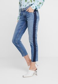 Slim fit džíny z denimu ve světle modré barvě s tmavě modrým bočním panelem. Zkrácená délka, s roztrhanými lemy a jemnými vybledlými detaily.