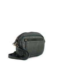 Grüne Leder-Crossbody-Tasche mit runder Form, ausgestattet mit einer vorderen Reißverschlusstasche und einem verstellbaren Tragegurt. Logo auf der Seite eingeprägt.