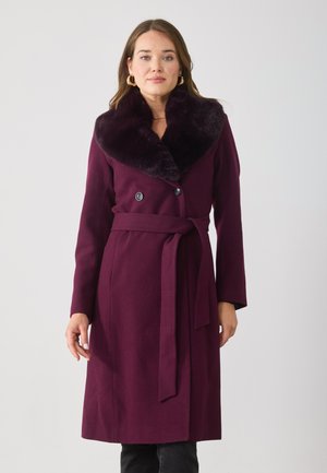 Paarse wollen jas met een faux fur kraag, dubbele knopen, tailleband en zijzakken. Gladde textuur en getailleerde pasvorm.