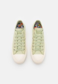 Baskets en toile vert clair avec embout en caoutchouc blanc, six œillets et lacets assortis. Dotées d'une semelle intérieure à motif coloré.