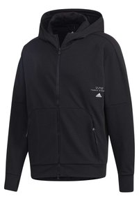 Svart zip-up hoodie i strukturväv. Har huva, ribbade muddar, fickor med dragkedja och tryckt logotyp på bröstet.