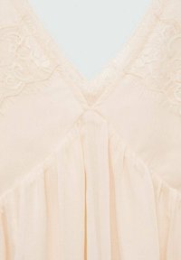 Vestido color melocotón con un delicado borde de encaje en el escote en V, tela suave y fluida, y diseño plisado para aportar textura adicional.