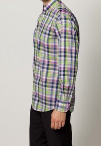 En knappad skjorta med rutigt mönster i grönt, lila och marinblått; tillverkad av bomull med klassisk krage och långa ärmar.