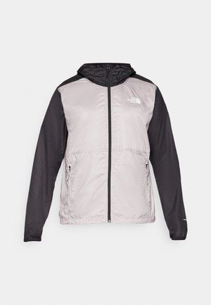 Giacca leggera con cappuccio, corpo grigio e maniche nere, dotata di zip completa, due tasche laterali e un logo sul petto.