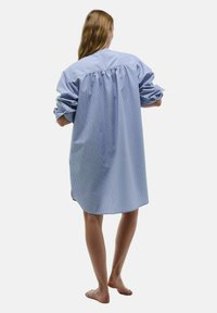 Robe chemise oversize à rayures bleues et blanches, manches longues, détail froncé au dos, en tissu coton, mi-longue avec ourlet arrondi.