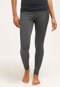 Grå idrottsleggings tillverkade av ett stretchigt tyg, med en mjuk yta, åtsittande design och sömdetaljer längs fram.