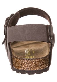 Sandale synthétique marron avec une large sangle, une boucle réglable et une semelle intérieure en liège texturé. Semelle plate avec un motif texturé pour une meilleure adhérence.