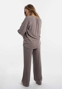 Losse, lichtgrijze top met gerimpeld achterpand, gecombineerd met bijpassende wijde broek. Glad stofmateriaal, casual ontwerp.