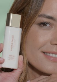 Hydra Prime SPF 50 zonnebrandfles, wit met gouden accenten, cilindervorm, met gelabelde tekst voor brede bescherming.
