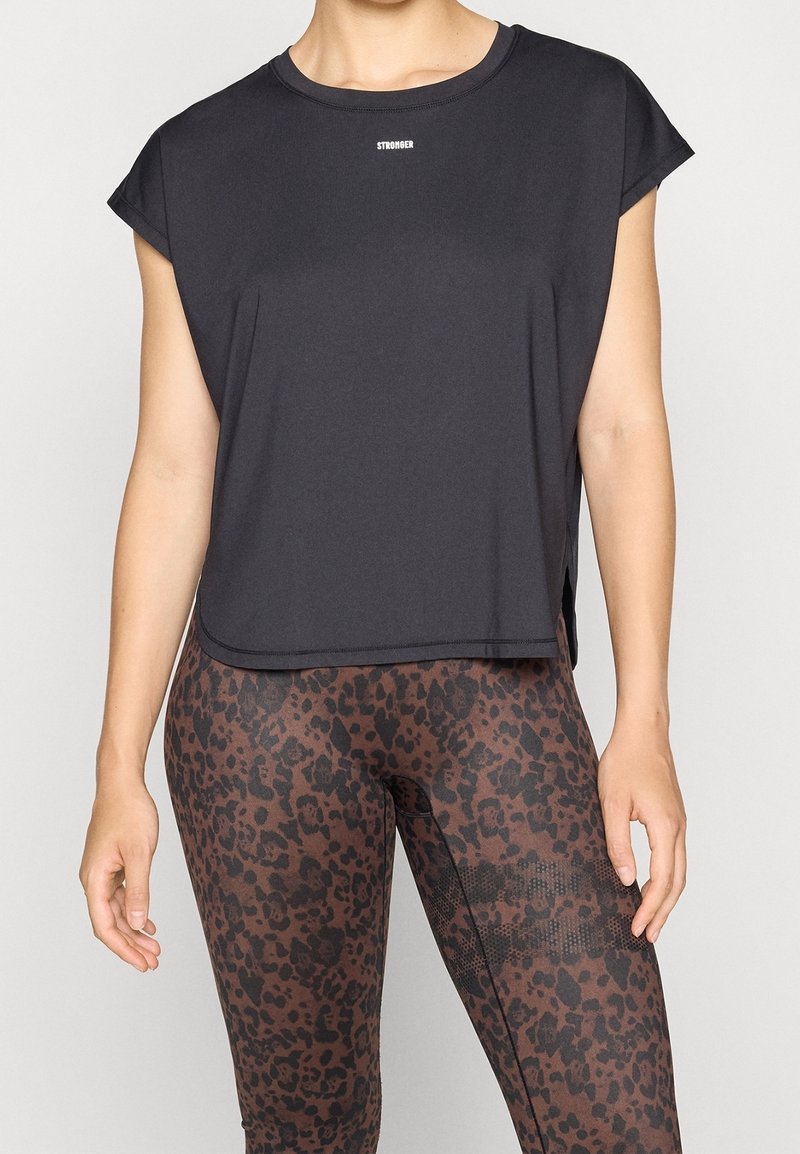 Sort kortærmet top med rund halsudskæring; sideslidser. Båret med brune leggings med leopardprint og tekstureret mønster.