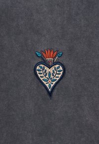 Καρδιοειδές κεντητό ύφασμα με μπλε φύλλα και κόκκινες φλόγες σε σκουρόφυλλο γκρι ύφασμα.