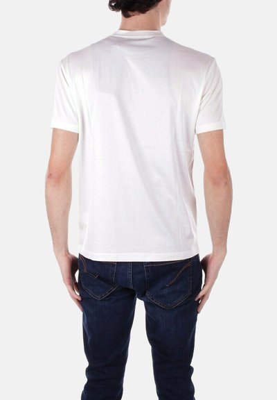 T-shirt bianca a maniche corte realizzata in tessuto morbido, con scollo rotondo e design semplice, indossata con jeans blu.