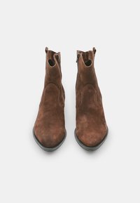 Botas de tobillo de ante marrón con una textura suave, punta afilada y cremalleras laterales. Presentan detalles de costura sutiles y un tacón bajo negro.