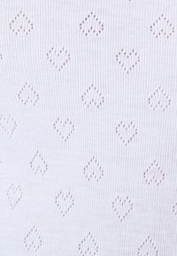 Tejido blanco de punto que presenta un patrón de pequeños corazones calados. La textura es suave con un diseño de puntada uniforme.