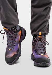 Scarpe da trekking viola e nere con finitura texturizzata, caratterizzate da accenti arancioni e lacci decorati, progettate per terreni impervi.