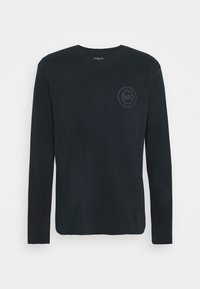 Camiseta de algodão preta de mangas longas com um decote redondo e um gráfico de logótipo subtil na área do peito esquerdo. Textura suave, design casual.