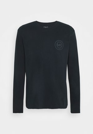 Camiseta de algodão preta de mangas longas com um decote redondo e um gráfico de logótipo subtil na área do peito esquerdo. Textura suave, design casual.
