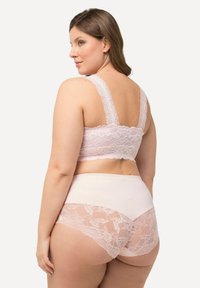 Kanten bralette in lichtroze met brede bandjes en een zachte onderband, gecombineerd met hooghoge onderbroeken met kant en een effen paneel.