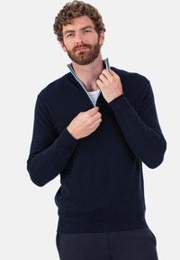 Pull-over bleu marine en tissu tricoté avec un col zippé. Caractérisé par des manches longues et un ourlet côtelé, avec une texture douce.