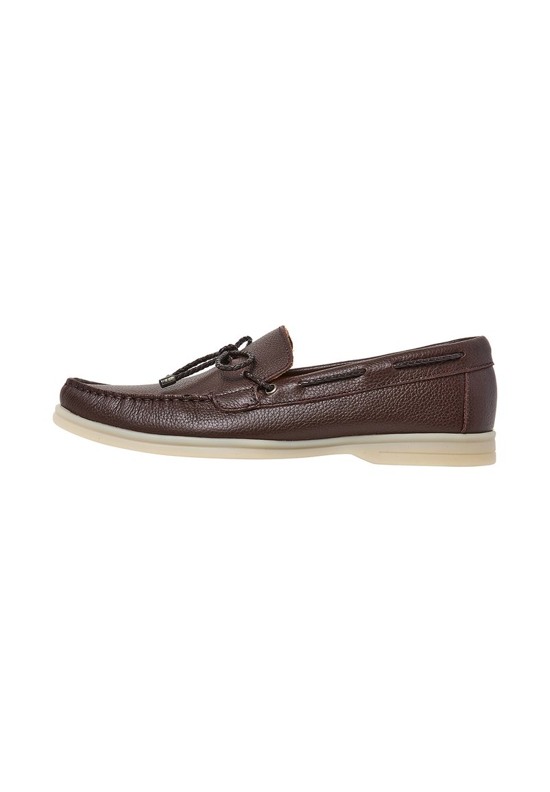 Chaussure en cuir marron de style mocassin avec une surface texturée, un détail de lacet décoratif et une semelle beige clair contrastante.