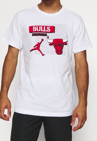 Camiseta de algodón blanca con un gráfico rojo de la cabeza de un toro y la silueta de un jugador de baloncesto, con texto "BULLS" y "CHICAGO".