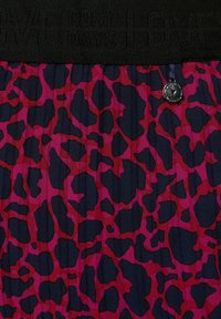 Cinturilla elástica negra con texto grabado. La tela presenta un fondo azul marino y un patrón vibrante de manchas de leopardo en rosa y rojo con un detalle brillante.